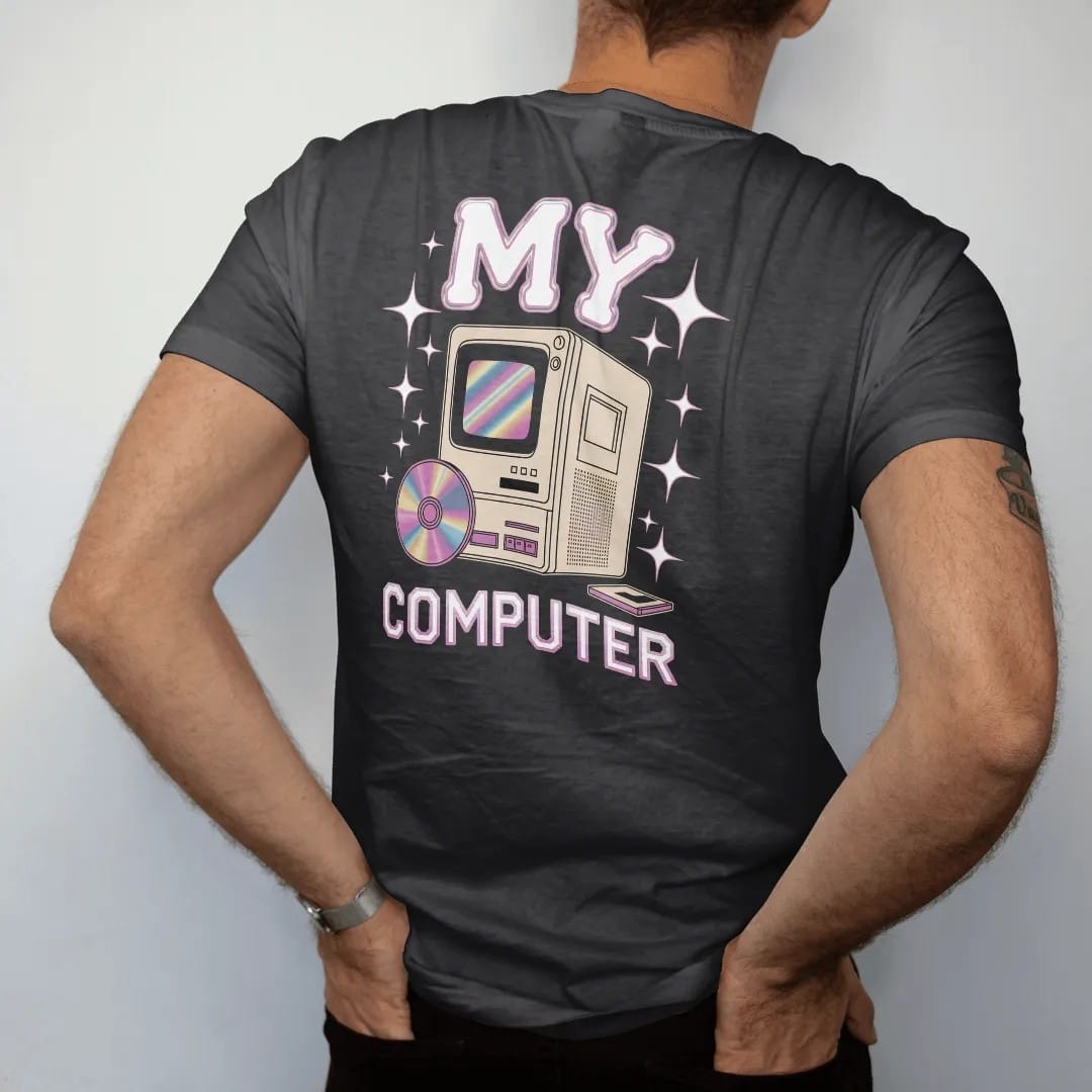 Man wearing a Black tee, seen from the back: a chunky beige desktop tower with an open disc tray, with "MY" and "COMPUTER" in liquid-chrome bubble letters and small pixel type, printed in glossy gunmetal chrome, cobalt, hot magenta and violet with…