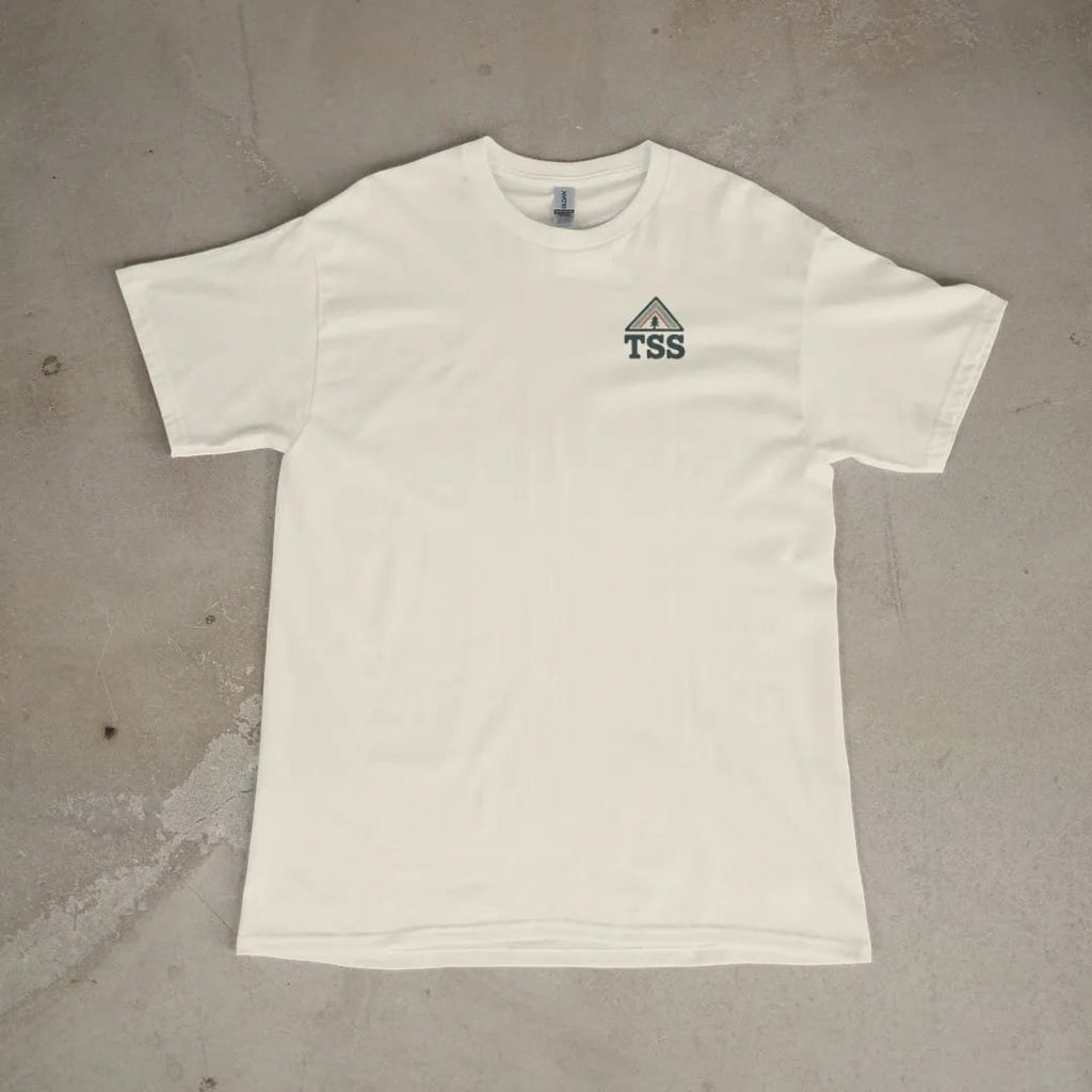 Front of a Ivory tee laid flat, with the small Trailhead Standard logo on the left chest.