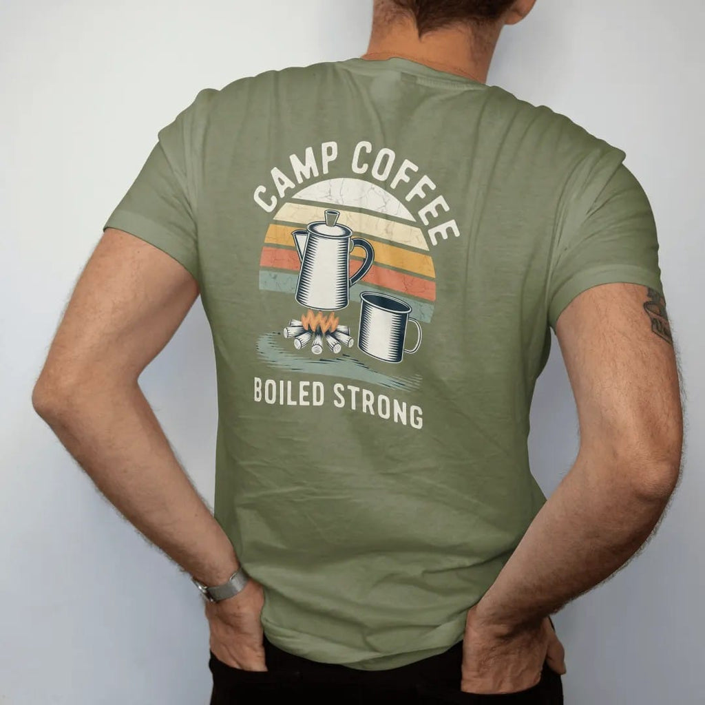 Man wearing a Moss tee, seen from the back: an enamel percolator steaming over a small campfire with a tin mug beside it, label-style layout, faded 70s park-souvenir style, lettered "CAMP COFFEE / BOILED STRONG" in chunky rounded 70s letters with a…