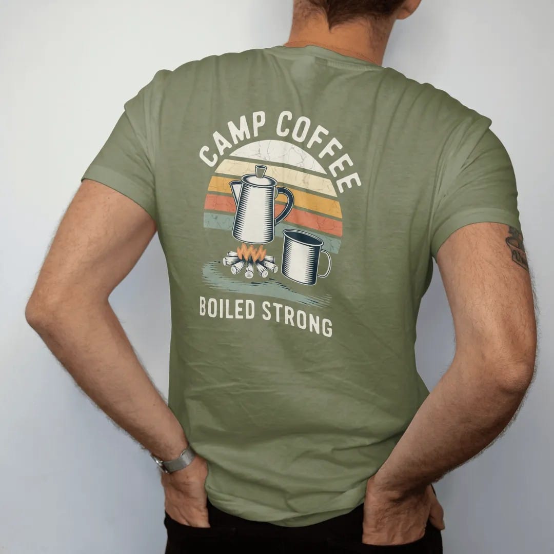 Man wearing a Moss tee, seen from the back: an enamel percolator steaming over a small campfire with a tin mug beside it, label-style layout, faded 70s park-souvenir style, lettered "CAMP COFFEE / BOILED STRONG" in chunky rounded 70s letters with a…