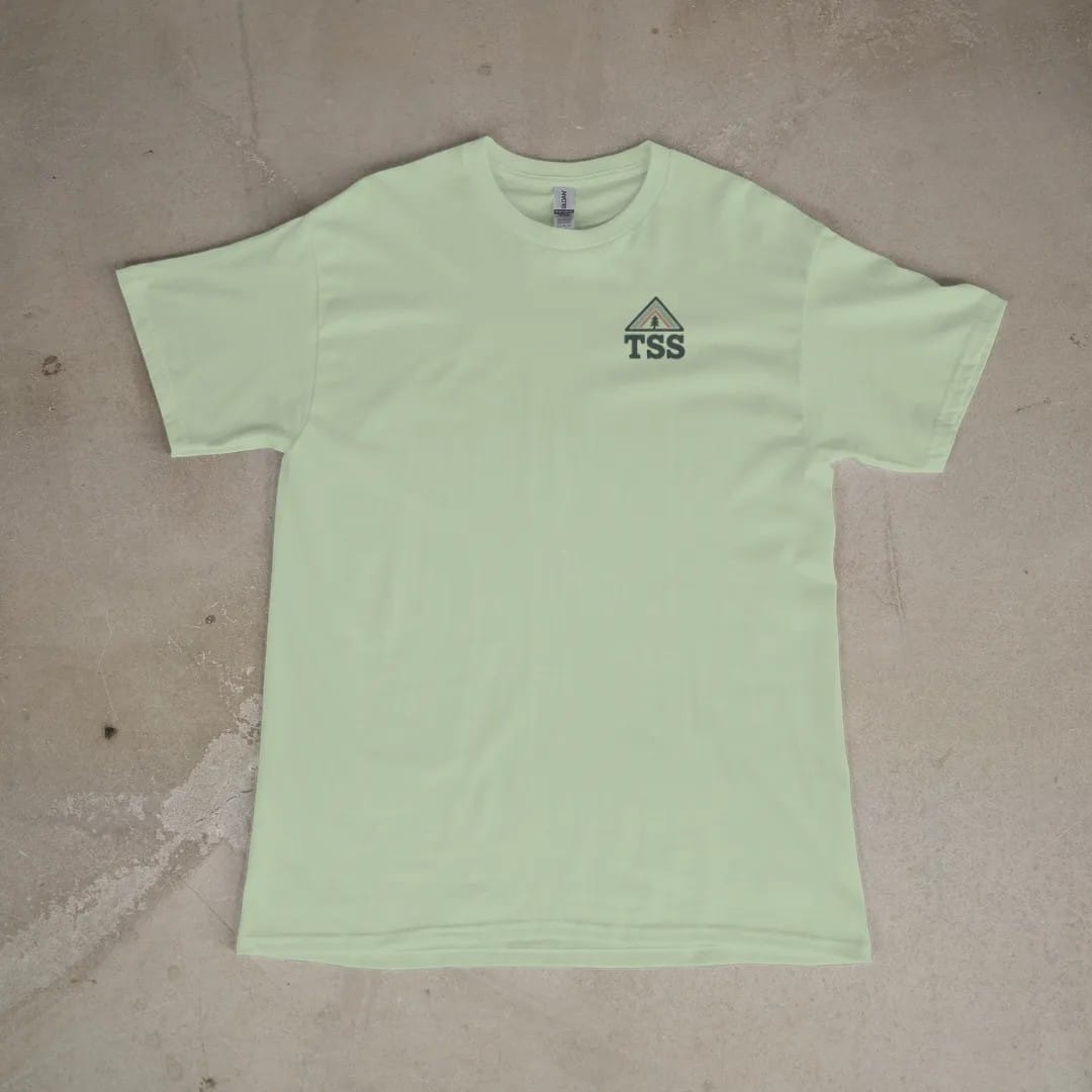 Front of a Light Green tee laid flat, with the small Trailhead Standard logo on the left chest.