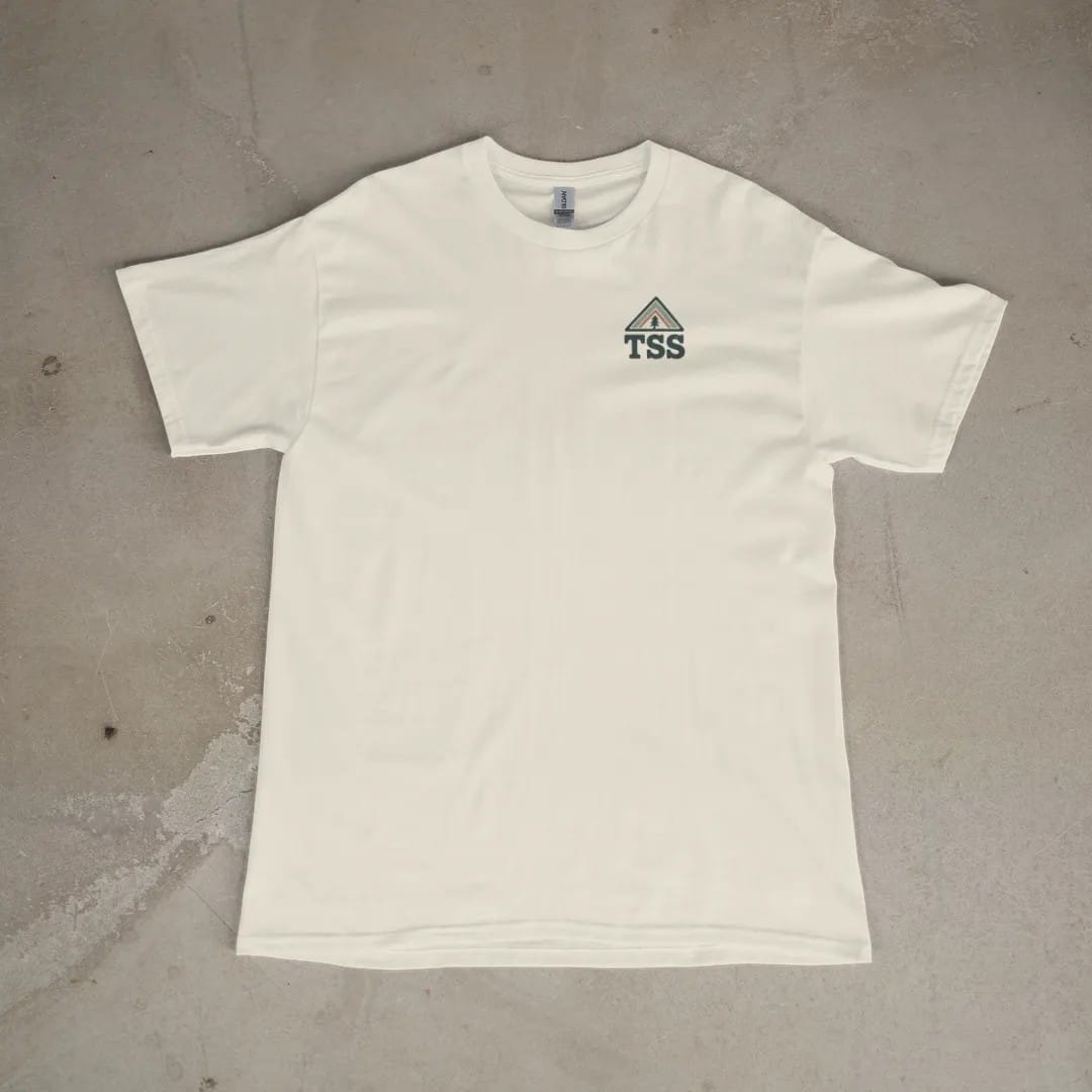 Front of a Ivory tee laid flat, with the small Trailhead Standard logo on the left chest.