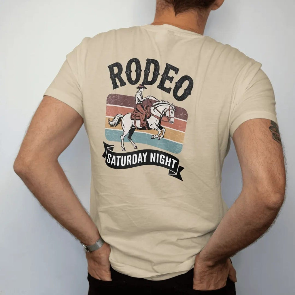Man wearing a Sandstone tee, seen from the back: vintage rodeo poster layout with a bucking bronco and rider, "RODEO" in huge chunky 70s slab letters above and "SATURDAY NIGHT" on a banner below, in a faded 1970s souvenir style with a worn…