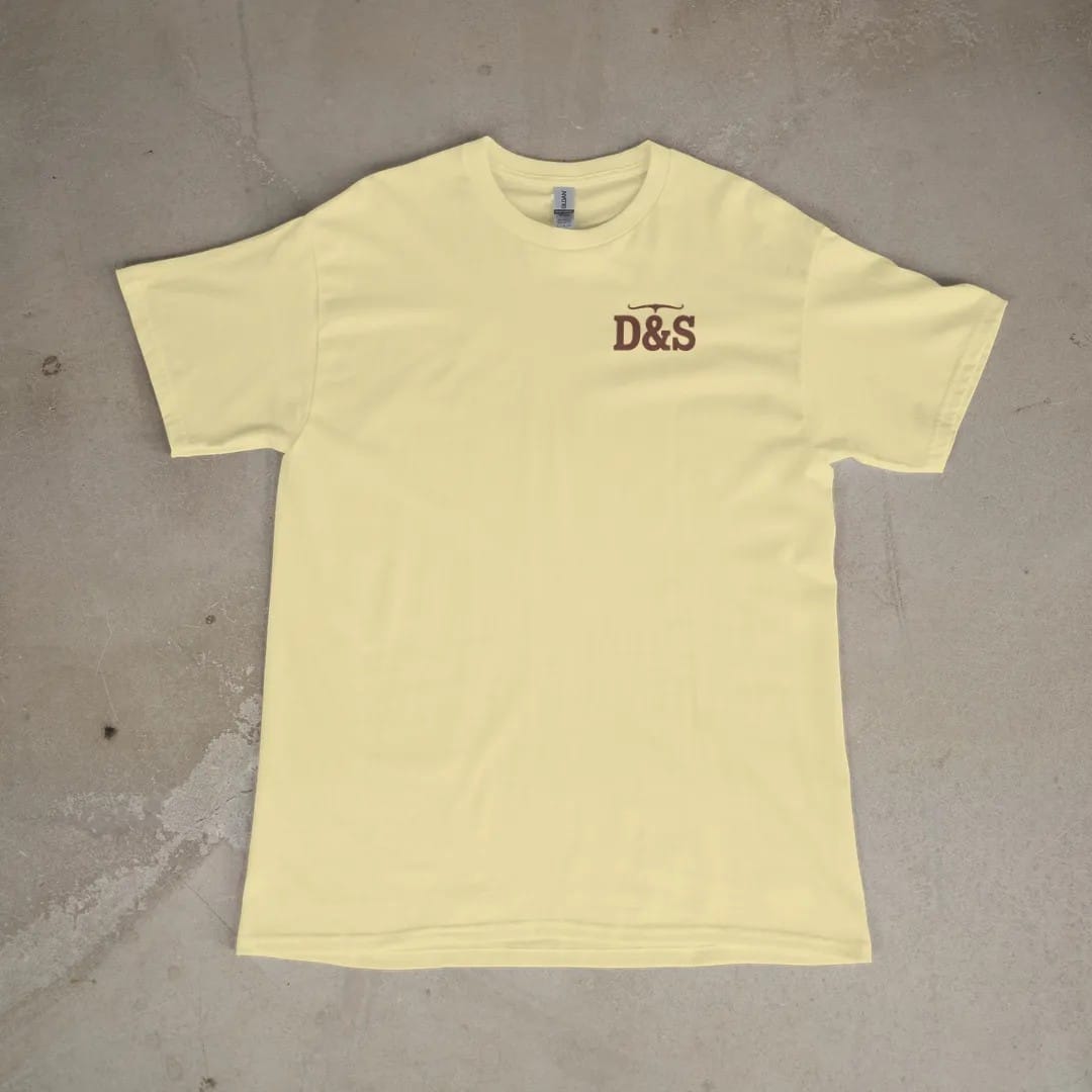 Front of a Butter tee laid flat, with the small Dust & Spur logo on the left chest.