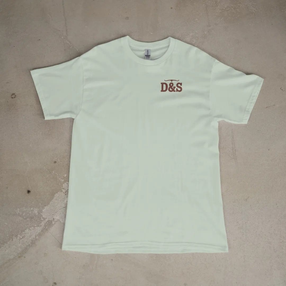 Front of a Bay tee laid flat, with the small Dust & Spur logo on the left chest.