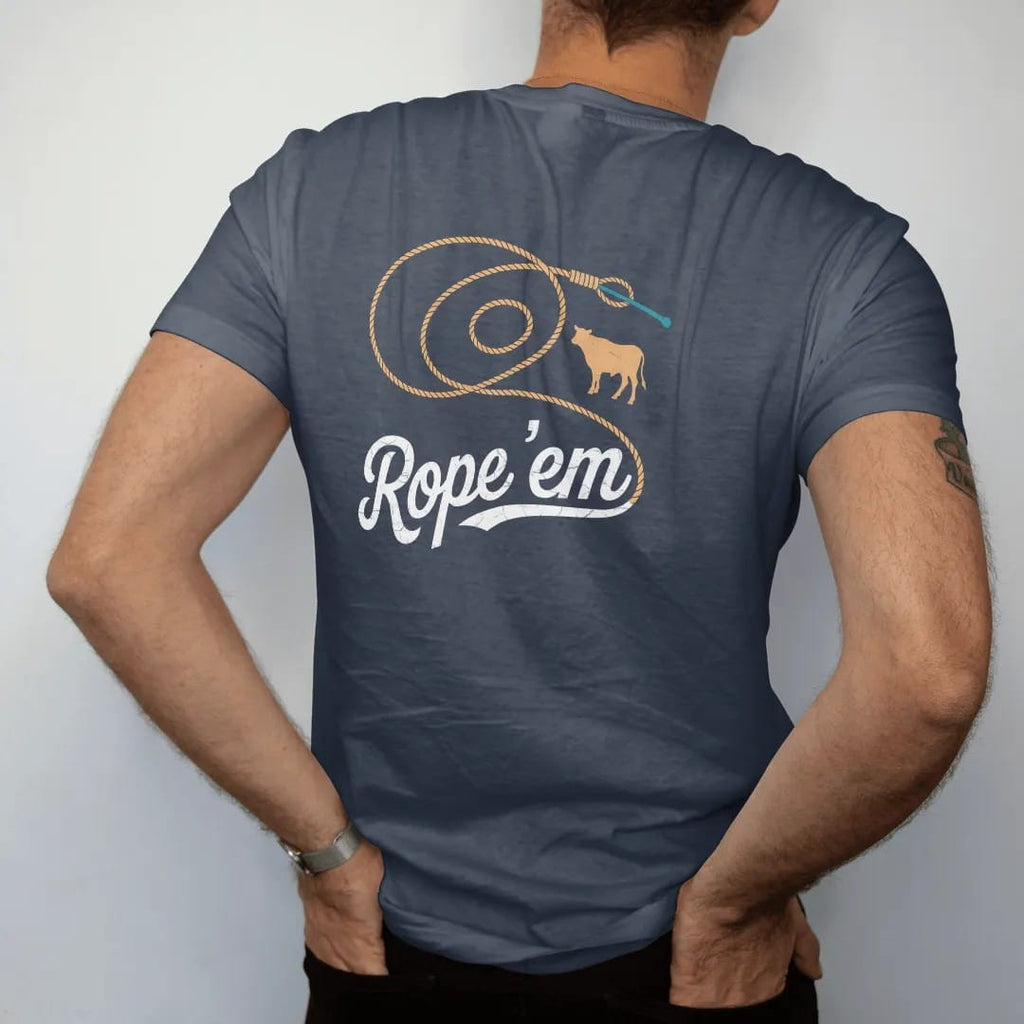 Man wearing a Midnight tee, seen from the back: a coiled lasso flying open into a big loop with a small calf silhouette, "ROPE 'EM" in a looping 70s rope script across the loop, in a faded 1970s souvenir style with a worn cracked-ink texture,…