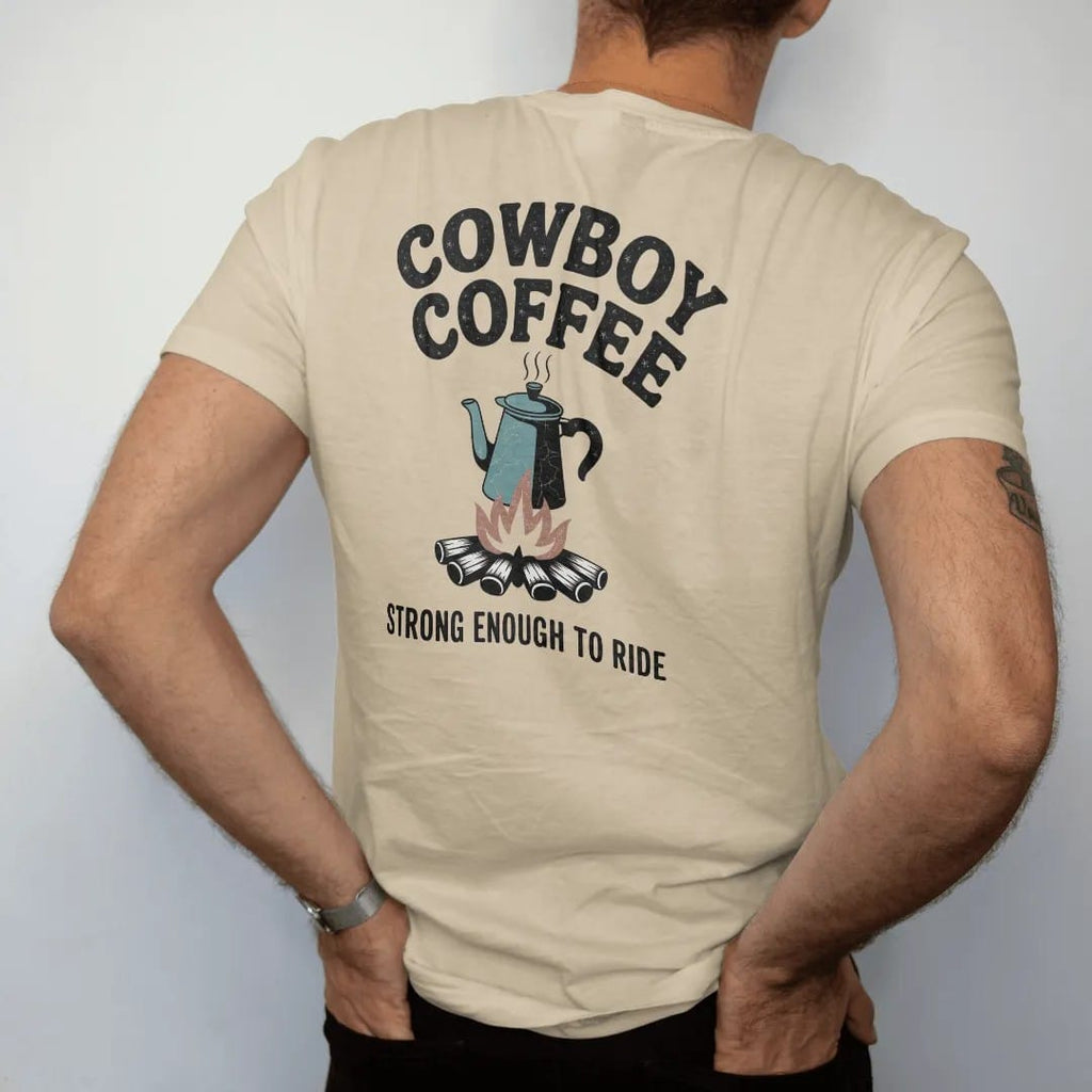 Man wearing a Sandstone tee, seen from the back: vintage ad parody of an enamel coffee pot over a campfire with steam, "COWBOY COFFEE" in a banner of chunky rounded 70s letters and "STRONG ENOUGH TO RIDE" small below, in a faded 1970s souvenir…