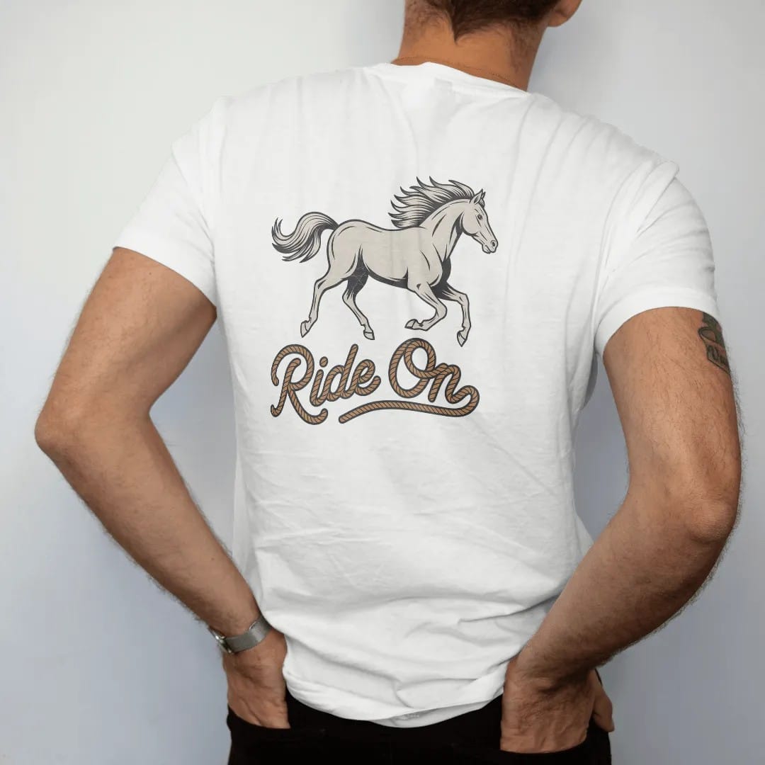 Man wearing a White tee, seen from the back: a galloping horse with flowing mane in mid-stride, "RIDE ON" in a looping 70s rope script beneath, in a faded 1970s souvenir style with a worn cracked-ink texture, printed in faded bone, sunset orange,…