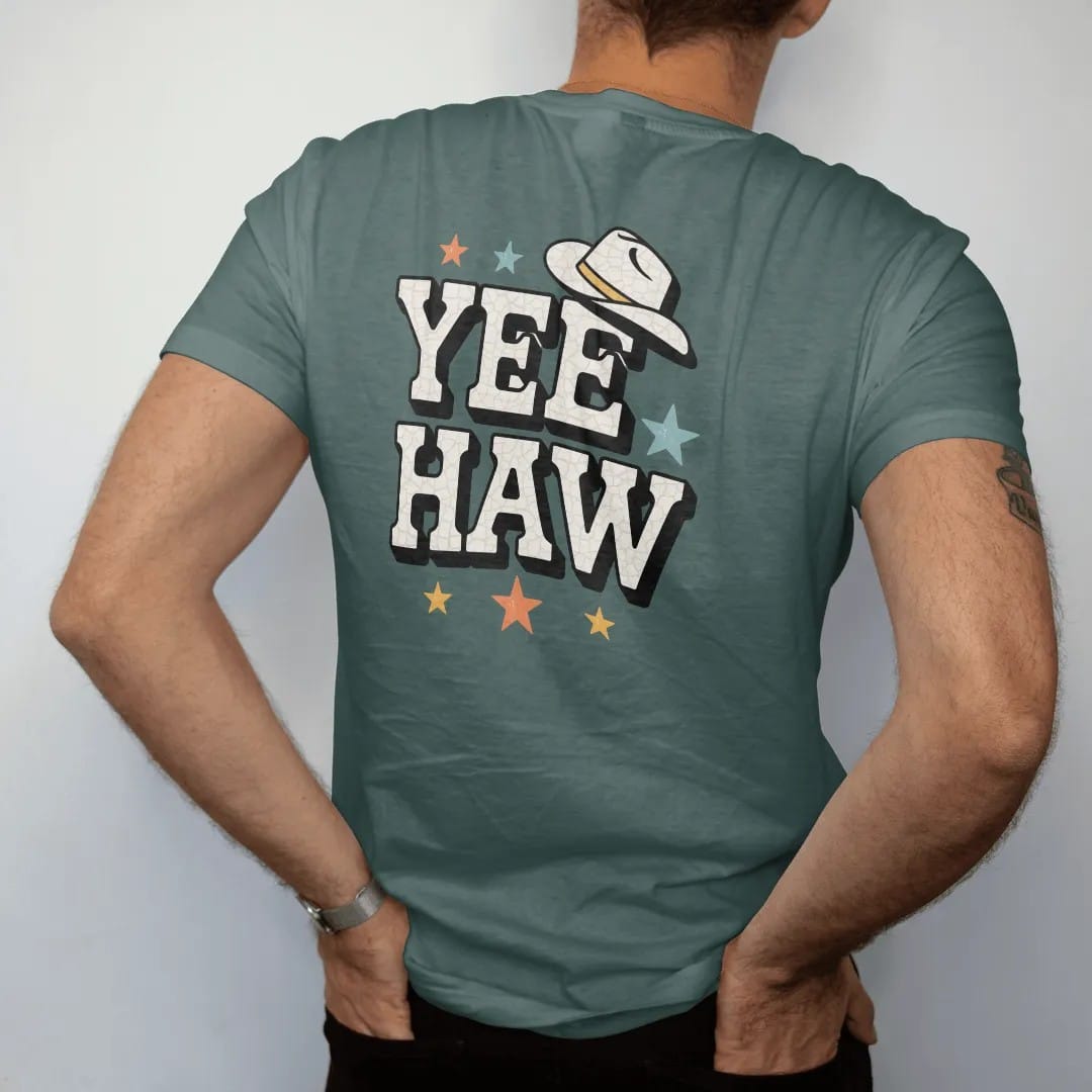 Man wearing a Blue Spruce tee, seen from the back: the single word "YEEHAW" in huge chunky 70s block letters with a small cowboy hat perched on the first Y and a few stars around it, in a faded 1970s souvenir style with a worn cracked-ink texture,…