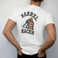 Man wearing a White tee, seen from the back: a barrel racer leaning hard around a barrel with dust flying, "BARREL" arched above and "RACER" below in chunky 70s slab letters, in a faded 1970s souvenir style with a worn cracked-ink texture, printed…