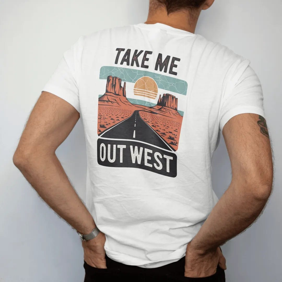 Man wearing a White tee, seen from the back: a vintage travel postcard scene of mesas, a winding road and a big sun, "TAKE ME" in small caps above and "OUT WEST" in large faded 70s souvenir-sign lettering below, in a faded 1970s souvenir style with…