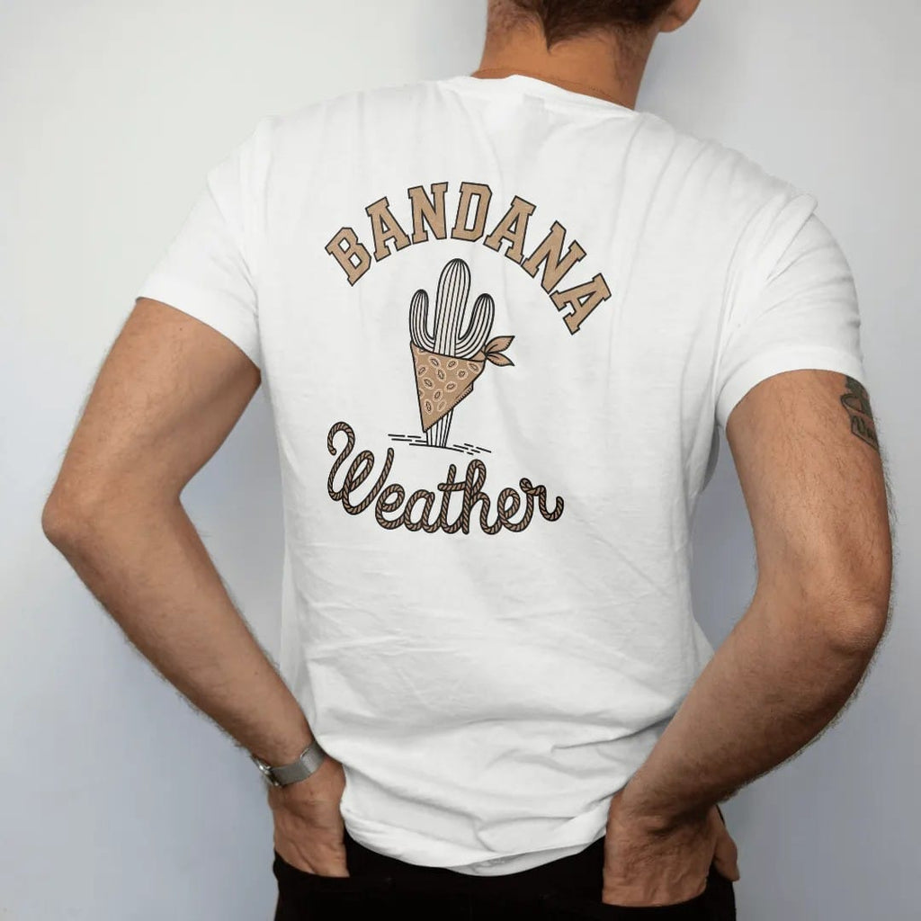Man wearing a White tee, seen from the back: a folded paisley bandana tied around a small cactus, "BANDANA" in chunky 70s block letters above and "WEATHER" in a looping 70s rope script below, in a faded 1970s souvenir style with a worn cracked-ink…