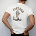 Man wearing a White tee, seen from the back: a folded paisley bandana tied around a small cactus, "BANDANA" in chunky 70s block letters above and "WEATHER" in a looping 70s rope script below, in a faded 1970s souvenir style with a worn cracked-ink…