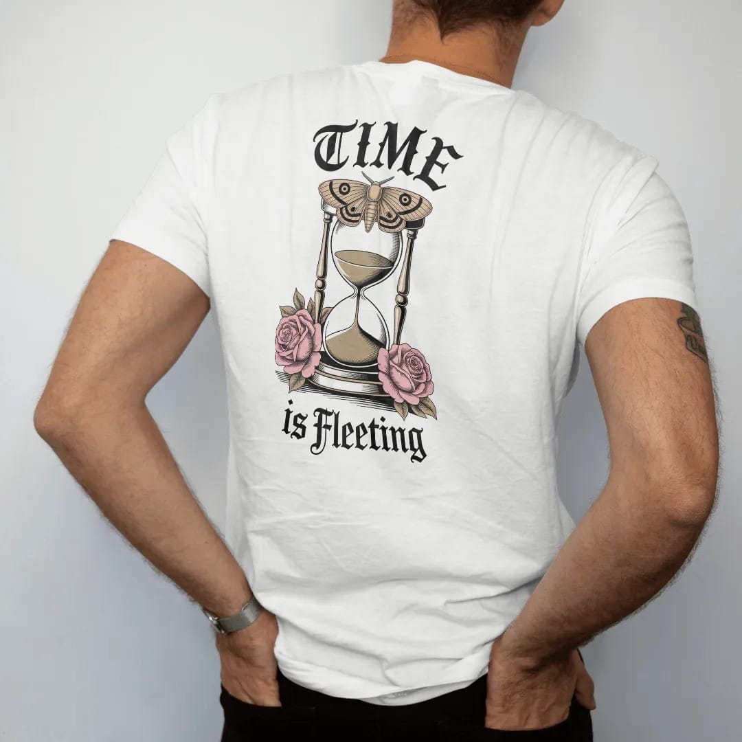 Man wearing a White tee, seen from the back: back print: ornate hourglass with sand running out, a moth resting on top and roses at the base, Victorian engraving style, "TIME" above in ornate gothic blackletter, "IS FLEETING" below in thin…