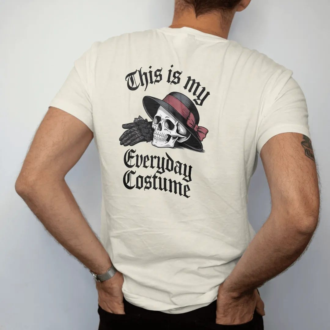 Man wearing a Ivory tee, seen from the back: back print: pair of black lace gloves and a veiled hat beside a small skull, Victorian fashion-plate engraving, "THIS IS MY" above in thin copperplate script, "EVERYDAY" in ornate blackletter, "COSTUME"…