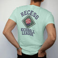 Man wearing a Chalky Mint tee, seen from the back: a bouncing red kickball over a chalk-drawn diamond, with "RECESS" and "KICKBALL LEAGUE" in chunky rounded 70s block letters, printed in faded varsity navy, washed red, mustard gold and pine green…