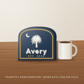 Palmetto and moon layered 3D printed nameplate reading Avery on a desk next to a mug