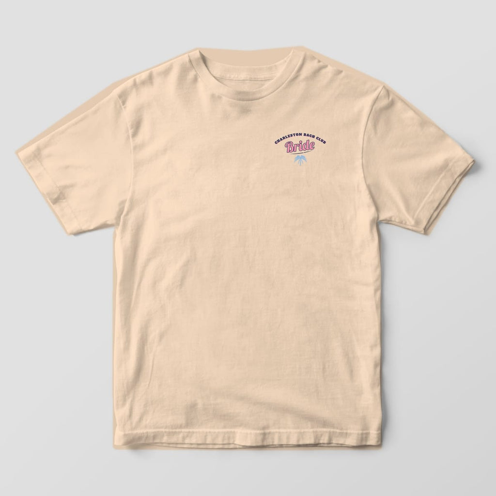 Front of an ivory Comfort Colors 1717 tee with a small left-chest print reading Charleston Bach Club around a pink Bride script and palmetto.