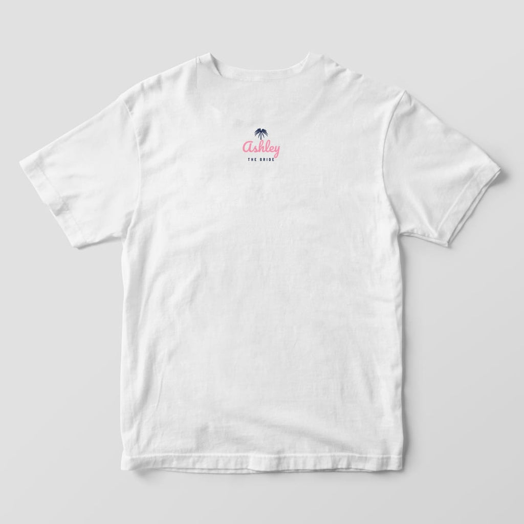 Back of a white Comfort Colors 1717 tee with a small navy palmetto, Ashley in pink script and THE BRIDE below the collar. A BRIDE'S CREW version is offered.