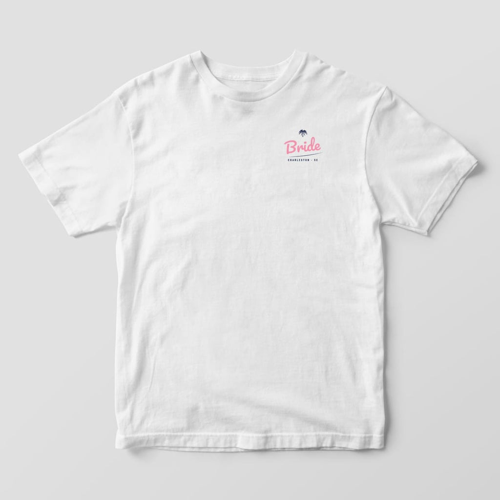 Front of a white Comfort Colors 1717 tee with a pink script Bride and tiny palmetto on the left chest, with CHARLESTON · SC beneath.