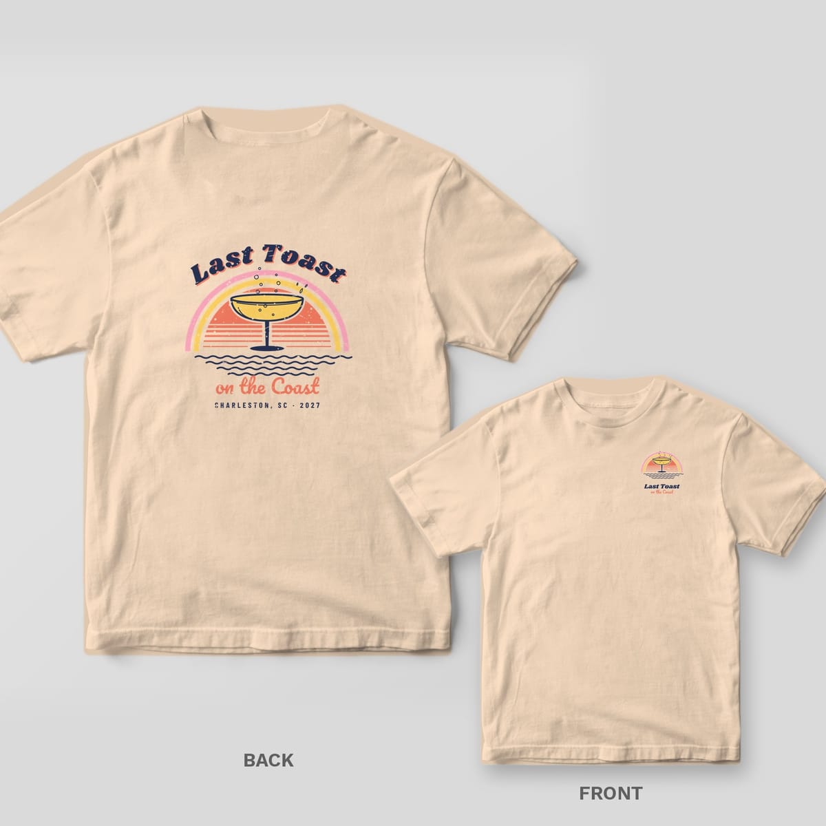 Ivory Comfort Colors tee with a retro back print of a champagne coupe over a striped sunset and waves, reading Last Toast on the Coast, plus a chest print inset.