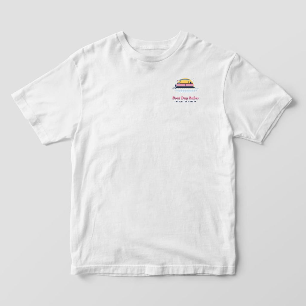 Front of a white Comfort Colors 1717 tee with a small pontoon boat and sun chest print and Boat Day Babes script.