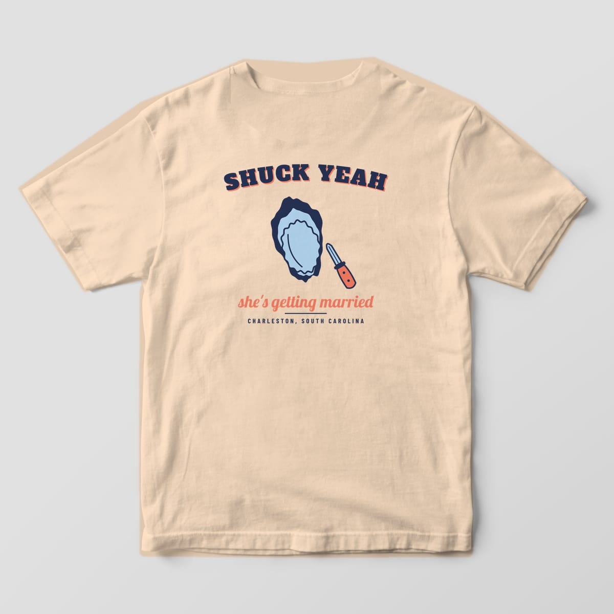 Back of an ivory Comfort Colors 1717 tee with arched navy SHUCK YEAH, a blue and navy oyster, a coral-handled knife and Charleston, South Carolina.