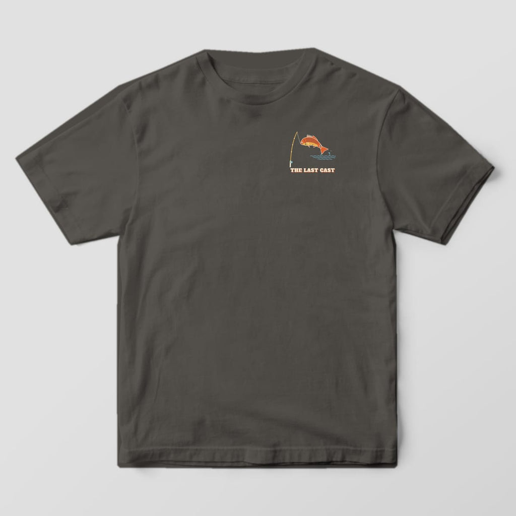 Front of a pepper Comfort Colors 1717 tee with a small redfish and fishing rod chest print reading The Last Cast.
