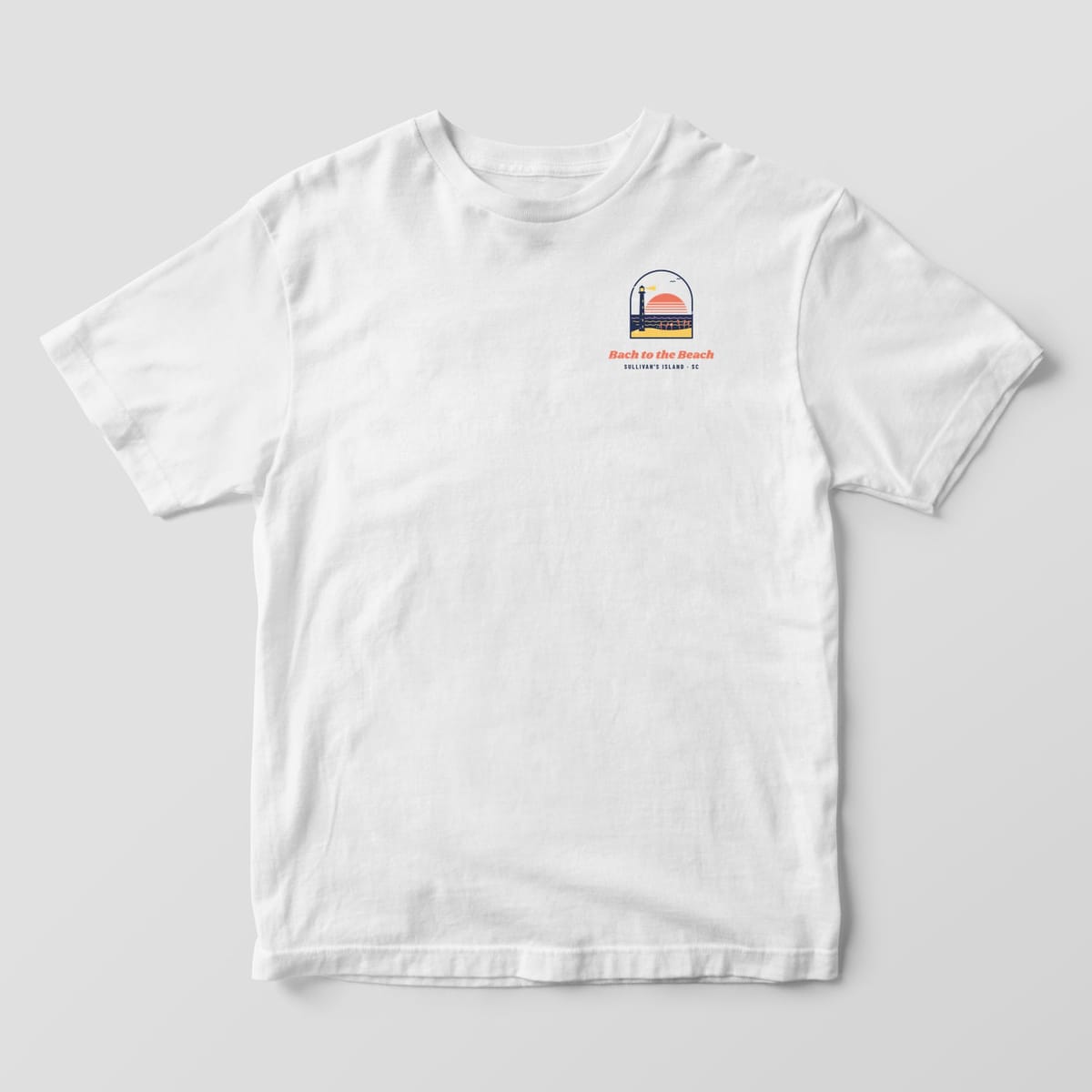 Front of a white Comfort Colors 1717 tee with a small arched beach and lighthouse chest print and Bach to the Beach lettering.