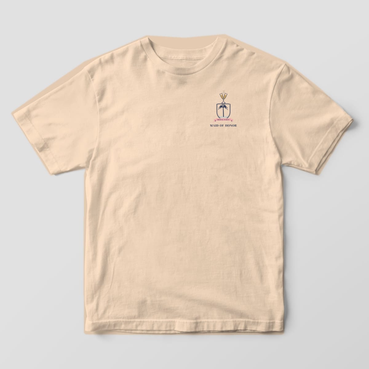 Front of an Ivory Comfort Colors tee with a small palmetto and champagne crest and MAID OF HONOR on the left chest